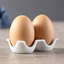 Load image into Gallery viewer, Brown Egg Salt Pepper Shaker Set by Allthingscurated are made of high-quality ceramic and designed to resemble real eggs. These shakers come with a try to securely hold them in place. Perfect for your Easter table or as a thoughtful housewarming gift.