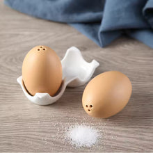 Load image into Gallery viewer, Brown Egg Salt Pepper Shaker Set by Allthingscurated are made of high-quality ceramic and designed to resemble real eggs. These shakers come with a try to securely hold them in place. Perfect for your Easter table or as a thoughtful housewarming gift.