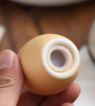 Load image into Gallery viewer, Brown Egg Salt Pepper Shaker Set by Allthingscurated are made of high-quality ceramic and designed to resemble real eggs. These shakers come with a try to securely hold them in place. Perfect for your Easter table or as a thoughtful housewarming gift.