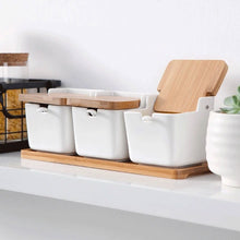 Load image into Gallery viewer, Ceramic Seasoning Storage Jars by Allthingscurated are the perfect storage solution to keep your herbs, seasonings and spices. Made of durable ceramic with a sustainable bamboo flip lid for easy access during cooking. These jars are not only functional but also environmentally friendly. Comes with a bamboo tray and ceramic spoons.