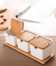 Load image into Gallery viewer, Ceramic Seasoning Storage Jars by Allthingscurated are the perfect storage solution to keep your herbs, seasonings and spices. Made of durable ceramic with a sustainable bamboo flip lid for easy access during cooking. These jars are not only functional but also environmentally friendly. Comes with a bamboo tray and ceramic spoons.