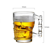 Load image into Gallery viewer, Skull Beer Mug by Allthingscurated blends functionality with style. Made with thickened glass with a heavy bottom for stability, it spots a fun, cool skull shape design that is ideal for Halloween or everyday use. The large capacity is perfect for beer or any beverage. Add this must-have mug to your drinkware collection and be ready for any gatherings or house parties. Measures 12.5cm or 4.9 inches in height and 9.5cm or 3.7 inches in diameter at the rim. Holds a capacity of 500ml or 17 ounce.