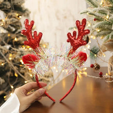 Load image into Gallery viewer, Add some sparkle to your holiday party with these Glittering Antler Christmas Headbands by Allthingscurated. Comes in 2 designs in Red or Gold. These beautiful accessories are perfect for hyping up the festive atmosphere. Featured here is the Red Antler headband embellished with tinsel.