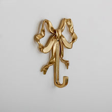 Load image into Gallery viewer, These pretty wall hooks by Allthingscurated are made of high-quality brass with a vintage gold finish.  Fashioned like a bow tied with ribbon, it’s feminine and perfect for the walk-in wardrobe or powder room. Comes in small and large size. Small hook measures 7.3cm or 2.8 inches in height and 6.5cm or 2.5 inches in width. Large hook measures 10.3cm or 4 inches in height and 9.5cm or 3.7 inches in width. Sold as individual hooks or a set of small and large hooks.