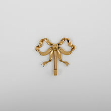 Load image into Gallery viewer, These pretty wall hooks by Allthingscurated are made of high-quality brass with a vintage gold finish.  Fashioned like a bow tied with ribbon, it’s feminine and perfect for the walk-in wardrobe or powder room. Comes in small and large size. Small hook measures 7.3cm or 2.8 inches in height and 6.5cm or 2.5 inches in width. Large hook measures 10.3cm or 4 inches in height and 9.5cm or 3.7 inches in width. Sold as individual hooks or a set of small and large hooks. This is a small hook.
