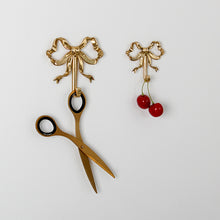 Load image into Gallery viewer, These pretty wall hooks by Allthingscurated are made of high-quality brass with a vintage gold finish.  Fashioned like a bow tied with ribbon, it’s feminine and perfect for the walk-in wardrobe or powder room. Comes in small and large size. Small hook measures 7.3cm or 2.8 inches in height and 6.5cm or 2.5 inches in width. Large hook measures 10.3cm or 4 inches in height and 9.5cm or 3.7 inches in width. Sold as individual hooks or a set of small and large hooks.