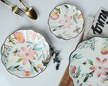 Load image into Gallery viewer, Allthingscurated’s Camille dinnerware features hand-painted florals, fauna and pretty butterflies and a color scheme of pink, yellow, blue,green and brown against a white ceramic background. Every plate is designed with a brown-lined scallop edge. Available in 6, 8 and 10 inches or 15.5, 20 and 25.5cm.