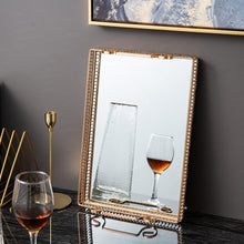 Load image into Gallery viewer, Donatella Mirror tray by Allthingscurated features a mirror surface and intricate gold-gilded pattern surround all sides of the rectangle tray and with 2 handles. Available in small, medium and large size. Featured here is a large rectangle tray leaning agains the wall. The surface of the tray can eve become a mirror on its own.