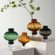 Load image into Gallery viewer, Luna Lantern Vases by Allthingscurated are stylish and versatile. Crafted from high-quality thick glass and creatively shaped like an Oriental Lantern with a strong aesthetic, they are perfect for creative floral arrangement or simply as a decorative display on its own. Comes in 2 sizes and 3 avaliable colors of green, gray and amber.