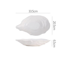 Load image into Gallery viewer, Oyster Shape Serving Dish by Allthingscurated is elegantly crafted in pristine white ceramic to mirror the contours and texture of the elegant oyster. The striking serve ware comes in multiple sizes for plating appetizers or main courses. Seen here is 33.5cm or 13.25 inches oyster dish.
