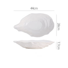 Load image into Gallery viewer, Oyster Shape Serving Dish by Allthingscurated is elegantly crafted in pristine white ceramic to mirror the contours and texture of the elegant oyster. The striking serve ware comes in multiple sizes for plating appetizers or main courses. Seen here is the 44cm or 17.25 inches oyster dish.
