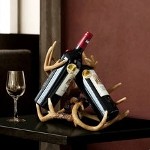 Load image into Gallery viewer, Antler Wine Bottle Holder by Allthingscurated is hand-crafted from resin and hand-painted to emulate the look of genuine antlers. Beautiful and sculptural, it’s a great gift for any occasion as well as a perfect addition to give your winter tablescape a cabin vibe. On its own, it’s a decorative, ornamental piece that gives a luxurious look to your mantel, tabletop or shelf. Measuring approximately 33cm or 13 inches in height, 35cm or 13.7 inches wide and a depth of 23cm or 9 inches.
