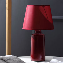 Load image into Gallery viewer, Burano Table Lamp by Allthingsucrated comes in 3 gorgeous colors in Red, Blue and Yellow.  The lamp base is made of ceramic and the lampshade of fabric.  Both the base and lampshade are of the same color.  Featured here is the red lamp in daylight.
