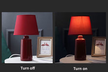 Load image into Gallery viewer, Burano Table Lamp by Allthingsucrated comes in 3 gorgeous colors in Red, Blue and Yellow.  The lamp base is made of ceramic and the lampshade of fabric.  Both the base and lampshade are of the same color.  Featuring the red lamp in both day and night effect.
