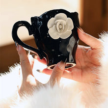 Load image into Gallery viewer, This Camellia Porcelain Cup Set / Mug by Allthingscurated features a single, significant bloom in a timeless black and white design that exudes sophistication. Its high fashion appeal makes it a perfect gift or impressive addition to your high-tea gatherings. Available as a mug or a cup set. Featured here is the Camellia Mug.
