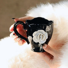 Load image into Gallery viewer, This Camellia Porcelain Cup Set / Mug by Allthingscurated features a single, significant bloom in a timeless black and white design that exudes sophistication. Its high fashion appeal makes it a perfect gift or impressive addition to your high-tea gatherings. Available as a mug or a cup set.
