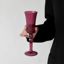 Load image into Gallery viewer, Cecily Flute Glasses by Allthingscurated feature a medieval-inspired vertical ridged design that provides a unique texture with an elegant touch. The long, sturdy stem ensures a steady hold while the jewel tones add a touch of sophistication to any celebration. Designed to complement your favorite wines, these glasses are perfect for entertaining and will brighten up any table. Featured here is flute glass in Magenta.
