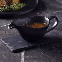 Load image into Gallery viewer, Curtis Ceramic Gravy Boat by Allthingscurated features an easy-to-hold handle and a narrow spout to ensure precise pouring without spills and drips. Available in white with a smooth, shiny glaze or black with a matte, rough finish. This versatile serveware with a capacity of 220ml or 7.4 fluid ounce is perfect for any occasion, formal or casual. 

