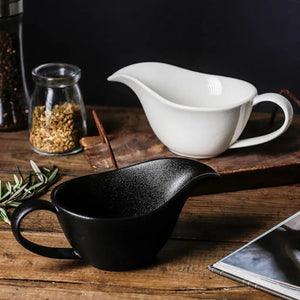 Curtis Ceramic Gravy Boat by Allthingscurated features an easy-to-hold handle and a narrow spout to ensure precise pouring without spills and drips. Available in white with a smooth, shiny glaze or black with a matte, rough finish. This versatile serveware with a capacity of 220ml or 7.4 fluid ounce is perfect for any occasion, formal or casual. 