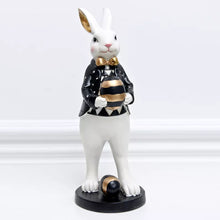 Load image into Gallery viewer, Our Regal Rabbit Family Figurines by Allthingscurated are beautifully-crafted and decorative. Made high-quality resin, these unique figurines will add a touch of elegance and whimsy to your home décor. Available in 6 designs, they are the perfect additions to your spring and Easter decorations. Featured here is Egg Holding Rabbit.
