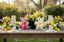 Load image into Gallery viewer, Six paper bunny decorations in pink, dark green, and beige on a wooden table in a garden setting. This curated set of two Honeycomb Easter Bunnies by Allthingscurated instantly transforms any space into a festive Easter wonderland. Their adorable silhouettes add personality and warmth to your holiday décor. Quick assembly and compact storage, with proper care, they remain beautiful year after year. Comes in 5 delightful colors.
