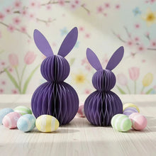 Load image into Gallery viewer, Two purple paper bunny decorations with pastel Easter eggs on a floral background. This curated set of two Honeycomb Easter Bunnies by Allthingscurated instantly transforms any space into a festive Easter wonderland. Their adorable silhouettes add personality and warmth to your holiday décor. Quick assembly and compact storage, with proper care, they remain beautiful year after year. Comes in 5 delightful colors.
