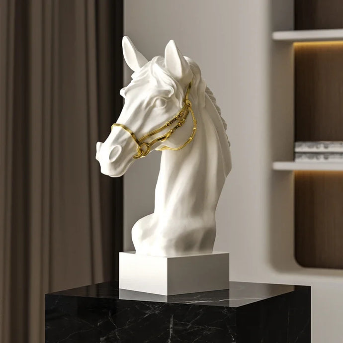 White horse head sculpture with gold bridle on a black marble surface. Fargo Horse Head Bust by Allthingscurated is an elegant decorative sculpture with meticulous detail and flaunts a gorgeous gold-accented bridle. Perfect for horse enthusiasts and makes a meaningful gift for those born under the Horse zodiac sign. And expertly crafted to complement both timeless classic and contemporary modern interiors.
