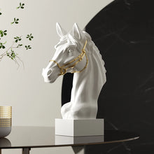 Load image into Gallery viewer, White horse head sculpture with gold bridle on a table against a neutral background. Fargo Horse Head Bust by Allthingscurated is an elegant decorative sculpture with meticulous detail and flaunts a gorgeous gold-accented bridle. Perfect for horse enthusiasts and makes a meaningful gift for those born under the Horse zodiac sign. And expertly crafted to complement both timeless classic and contemporary modern interiors.
