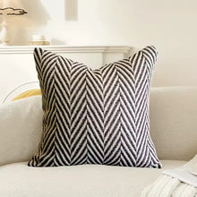 Load image into Gallery viewer, Black and white herringbone patterned pillow on a beige sofa by Allthingscurated.
