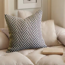 Load image into Gallery viewer, Herringbone patterned pillow on a sofa with a neutral background by Allthingscurated.
