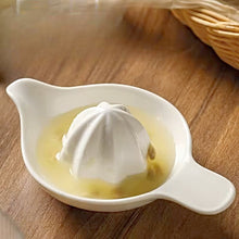 Load image into Gallery viewer, White citrus juicer with lemon juice on a wooden surface. Ceramic Citrus Juicer by Allthingscurated features a classic reamer design with built-in pour spout that ensures precise pouring without spills. This single-piece tool is easy to store and indispensable in any bar or kitchen.

