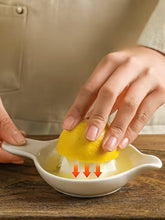 Load image into Gallery viewer, Person using a citrus juicer on a wooden surface. Ceramic Citrus Juicer by Allthingscurated features a classic reamer design with built-in pour spout that ensures precise pouring without spills. This single-piece tool is easy to store and indispensable in any bar or kitchen.
