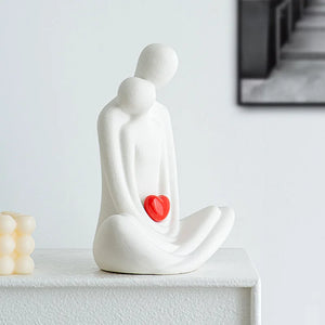 This romantic sculpture by Allthingscurated elegantly portrays a seated couple, locked in a tender embrace, their love and hearts held close. Sculpted in white ceramic, the piece highlights a striking red heart that symbolizes deep connection and passion. An ideal gift for Valentine’s Day or weddings, it offers a refined and timeless expression of affection.
