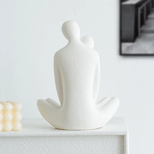 This romantic sculpture by Allthingscurated elegantly portrays a seated couple, locked in a tender embrace, their love and hearts held close. Sculpted in white ceramic, the piece highlights a striking red heart that symbolizes deep connection and passion. An ideal gift for Valentine’s Day or weddings, it offers a refined and timeless expression of affection.