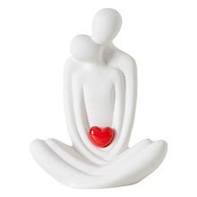 Load image into Gallery viewer, This romantic sculpture by Allthingscurated elegantly portrays a seated couple, locked in a tender embrace, their love and hearts held close. Sculpted in white ceramic, the piece highlights a striking red heart that symbolizes deep connection and passion. An ideal gift for Valentine’s Day or weddings, it offers a refined and timeless expression of affection.
