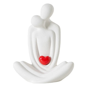 This romantic sculpture by Allthingscurated elegantly portrays a seated couple, locked in a tender embrace, their love and hearts held close. Sculpted in white ceramic, the piece highlights a striking red heart that symbolizes deep connection and passion. An ideal gift for Valentine’s Day or weddings, it offers a refined and timeless expression of affection.