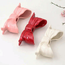 Load image into Gallery viewer, Three bow-shaped candle holders in pink, red, and white on a white background. Fashion Bow Candle Holder by Allthingscurated spots a distinctive knot design, beautiful yet practical. Perfect for wedding celebrations, home styling, or to infuse warmth and romance into any living space. Available in three colors and 2 sizes.
