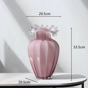 Anais Pink Beaded Vases by Allthingscurated are crafted from handblown glasses. Featuring a curvaceous body with an asymmetrical beaded rim that flares back like a collar.  Its captivating shape and romantic pink hue makes it a statement piece and a glamorous addition to your vase collection. Featured here is a large size. measuring 33.5cm or 13 inches in height and 20.5cm or 8 inches in width.