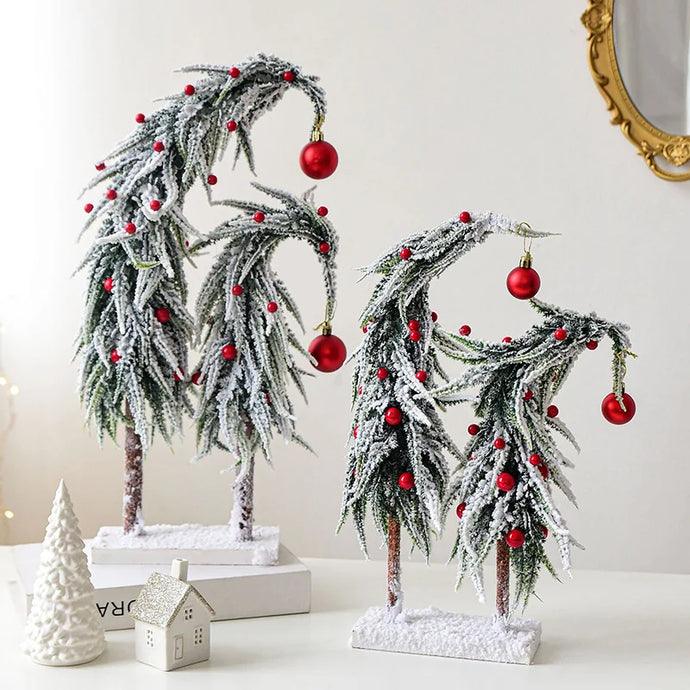 Snow Flocked Grinch Christmas Trees by Allthingscurated feature bending trees with a touch of quirkiness. The abstract design is both unconventional and whimsical. These snow-covered trees are decorated with crimson red baubles that will transform your home into a winter wonderland. Available in 2 sizes.