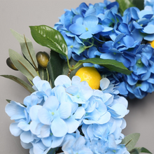 Load image into Gallery viewer, Summer Lemon Hydrangea wreath by Allthingscurated features a vibrant and cheerful yellow and blue color scheme, evoking images of sunny blue skies and warm summer days. The wreath adds a pop of color to your door and bring a little extra happiness to your home.

