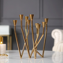 Load image into Gallery viewer, Lysa Gold Candelabra by Allthingscurated spots an asymmetrical design and clean lines that exude modern elegance. With 9 arms for taper candles, the gold-tone metal surface reflects the glow of the flames, creating a warm and captivating atmosphere. It’s stunning centerpiece for any occasion and decorative accent for any event or space.
