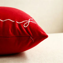 Load image into Gallery viewer, Red throw pillow with close zipper featuring red embroidered stitching of a ribbon bow in the corner, perfect for seasonal home decor.
