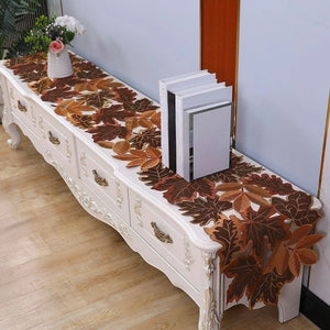 Decorative leaf-patterned table runner on a white console table with books and a vase. By Allthingscurated.