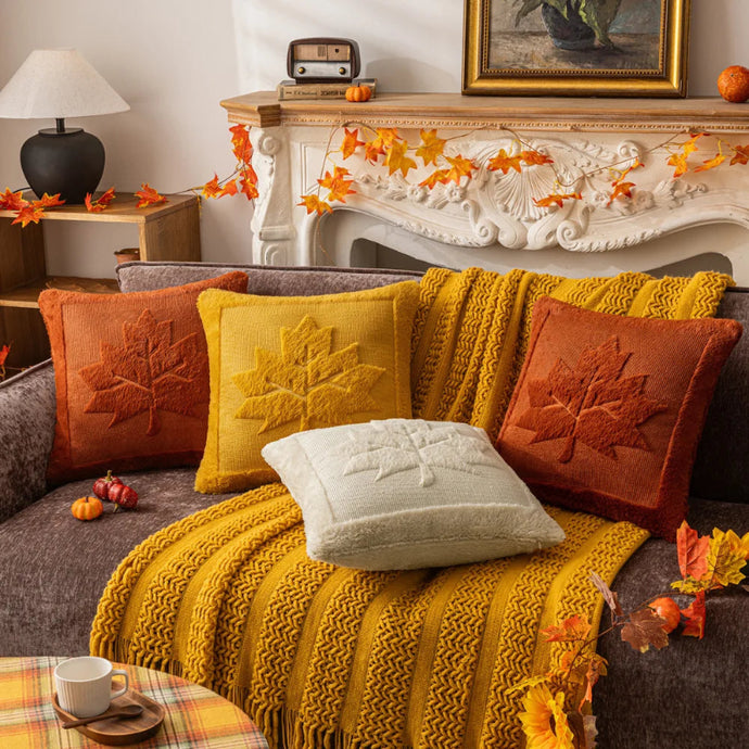 Cozy living room with a fireplace, decorated with autumn-themed pillows and decor. The Velour Maple Leaf Cushion Cover by Allthingscurated is a beautiful way to bring the warmth of fall into your home. With its elegant tufted pumpkin design and soft velour fabric, it offers both comfort and style. Perfect for autumn and Thanksgiving, this decorative pillow adds a cozy, inviting touch to any space.