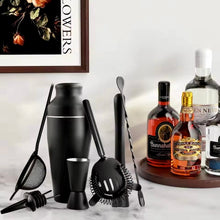 Load image into Gallery viewer, Bartending tools and liquor bottles on a marble surface with a framed picture in the background. Matte Black Parisian Cocktail Shaker 8-piece Set by Allthingscurated.
