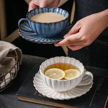 Load image into Gallery viewer, Two cups of tea, one blue and one white with lemon slices, on a dark surface. Japanese Chrysanthemum Cup and Saucer by Allthingscurated is inspired by the flower’s perfect symmetry and stunning beauty in the Japanese culture. Crafted from porcelain, it’s a beautiful set to entertain friends and family for afternoon teas at home.
