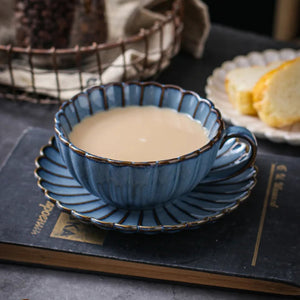 Blue ceramic cup with saucer containing a tea placed on a dark surface. Japanese Chrysanthemum Cup and Saucer by Allthingscurated is inspired by the flower’s perfect symmetry and stunning beauty in the Japanese culture. Crafted from porcelain, it’s a beautiful set to entertain friends and family for afternoon teas at home.