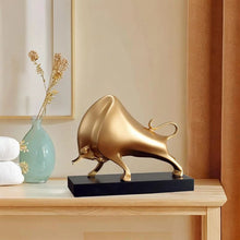 Load image into Gallery viewer, The Oscar Bull Sculpture by Allthingscurated spots an abstract and contemporary design in a matte gold finish. This stunning piece makes the perfect gift for those born under the zodiac ox sign and Taurus. It not only serves as a beautiful display but also adds a touch of personality. 
