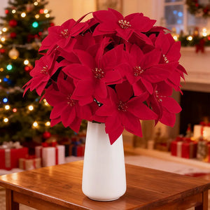 Red poinsettia flowers in a white vase on a wooden table with a Christmas tree in the background. Bring the true spirit of the holidays into your home with this bundle of 5 classic red Faux Poinsettia by Allthingscurated. These timeless blooms complement any festive palette and instantly evokes Christmas cheer.