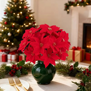 Red poinsettias in a green vase on a table with Christmas decorations in the background. Bring the true spirit of the holidays into your home with this bundle of 5 classic red Faux Poinsettia by Allthingscurated. These timeless blooms complement any festive palette and instantly evokes Christmas cheer.